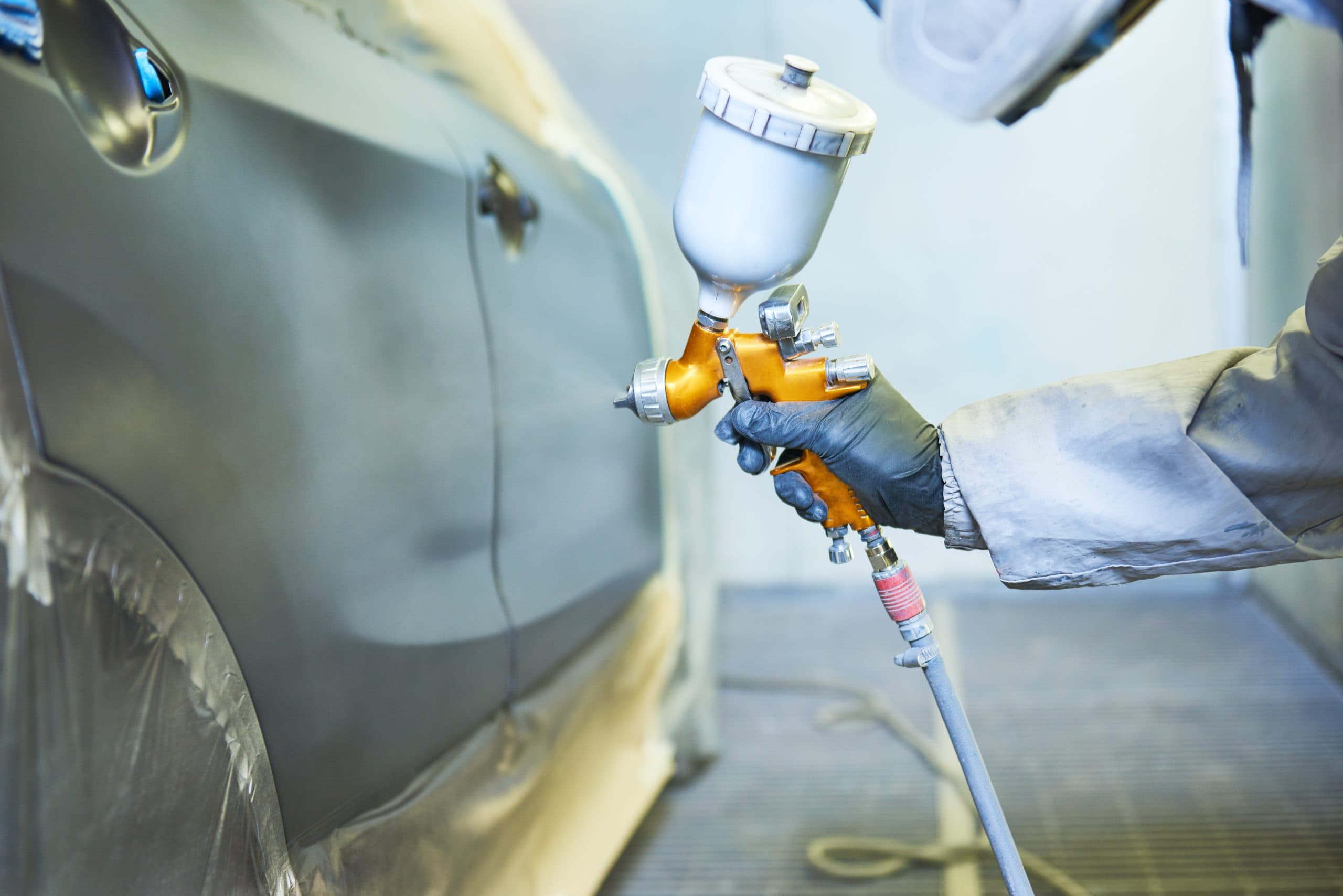 Technician applying paint with professional spray gun